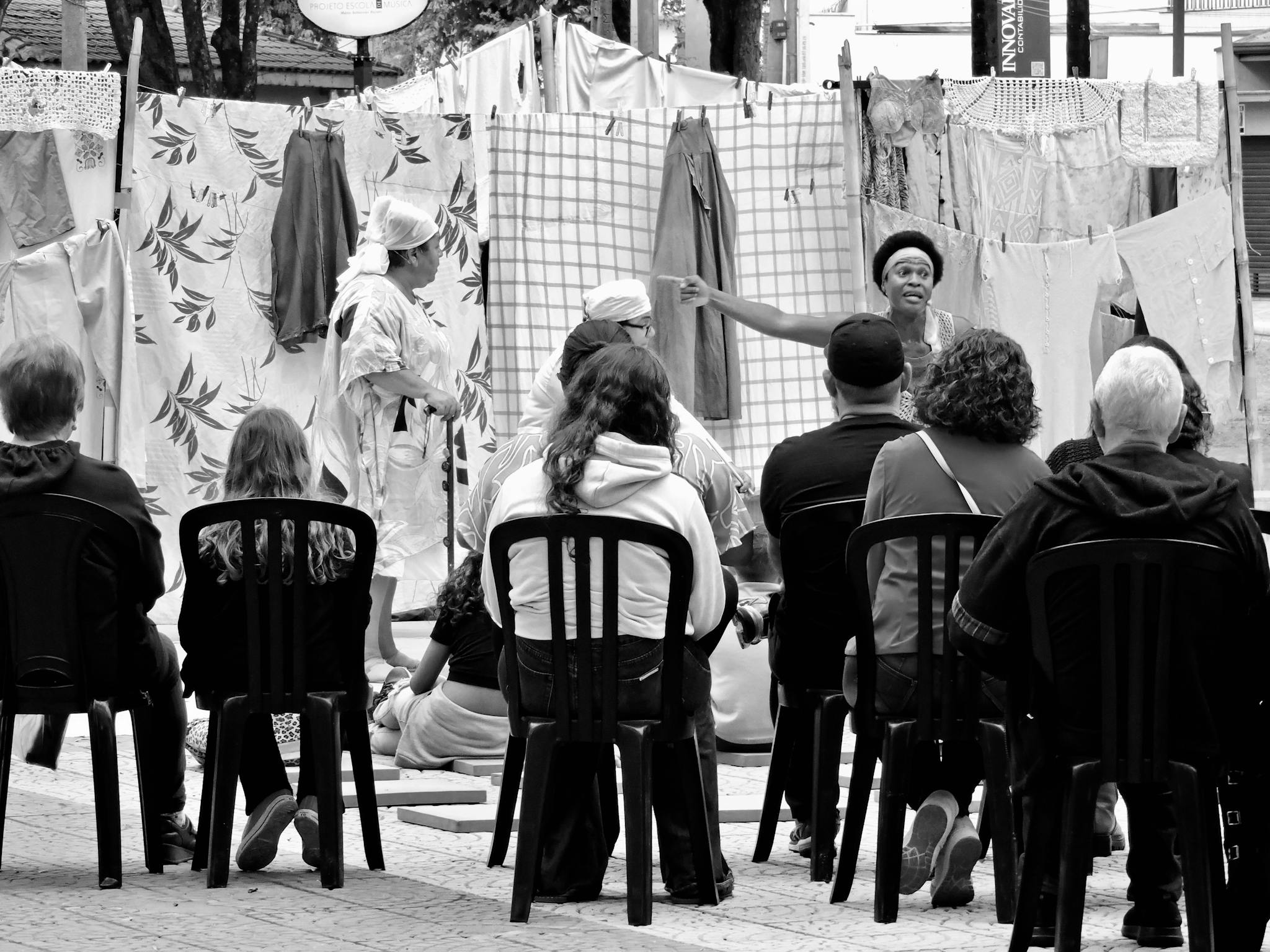 Street theater performance captured in black and white with an attentive audience outdoors.